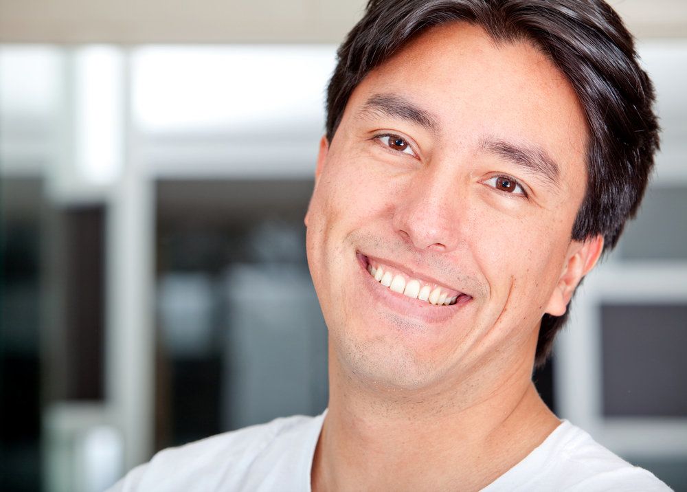 Smiling man with glossy dark hair tilting head back